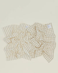 The Hawkins New York Essential Dish Towels in Flax/Ivory (Set of 2) are shown on a light surface; crafted from Oeko-Tex cotton, one towel features vertical stripes and the other a grid pattern.