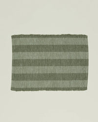 The Essential Floor Mat in Olive by Hawkins New York features recycled fibers with alternating dark and light green horizontal stripes set against a plain light background.