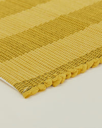 Close-up of the Essential Floor Runner in Mustard by Hawkins New York, showing its hand loomed checkered texture and knotted ends on a light surface—perfect as a floor runner and conveniently machine washable.