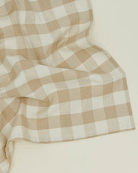 A set of Hawkins New York Essential Gingham Dinner Napkins in Ivory/Flax, featuring a beige and white checkered pattern, is laid out on a light surface.