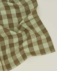 Hawkins New York Essential Gingham Dinner Napkins in Sage/Olive (set of 4) feature a stylish brown and light green plaid, slightly wrinkled—ideal for adding elegance to your table setting.
