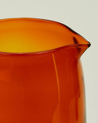 Close-up of the top edge and spout of a translucent Essential Glassware - Pitcher in Terracotta by Hawkins New York, set against a plain light background.