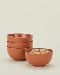 The Essential Large Bowls in Terracotta by Hawkins New York are shown—three stacked, one filled with cereal—highlighting this stylish set of 4, perfect for elevating any stoneware dinnerware collection.