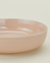 A close-up of the Hawkins New York Essential Low Bowls in Blush (Set of 4), featuring a smooth, glossy finish, set against a plain off-white background.