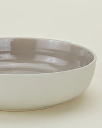 The Essential Low Bowls in Light Grey by Hawkins New York are shallow, round stoneware bowls with a matte white exterior and glossy light gray interior, shown against a plain, light background. Set of 4.