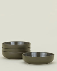 A set of four matte olive Essential Low Bowls from Hawkins New York are stacked on the left, with a fifth bowl placed separately on the right, all against a plain light background.