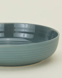 A close-up of Hawkins New York’s Essential Low Bowls in Peacock—set of 4—showing glossy interiors and matte, textured exteriors against a simple background.