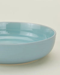 A close-up of the Hawkins New York Essential Low Bowls in Sky—set of 4—on a neutral background, highlighting this elegant stoneware dinnerware.