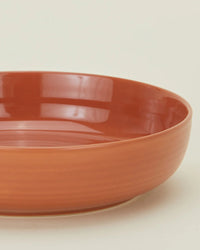 A close-up of the Hawkins New York Essential Low Bowls in Terracotta, a set of 4, showcases their round, shallow stoneware design against a plain light background.