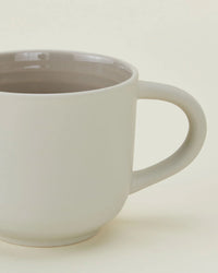 A close-up of Hawkins New Yorks Essential Mugs in Light Grey (Set of 4) shows their simple design and curved handles—perfect dishwasher safe mugs for everyday use.