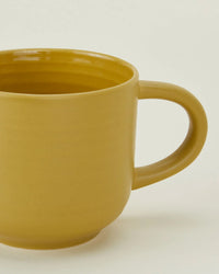 A mustard yellow Hawkins New York Essential Mug with a handle, shown against a plain light background. Sold as a set of 4 stoneware mugs.