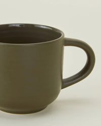 A close-up of Hawkins New Yorks Essential Mugs in Olive—set of 4—plain stoneware mugs with handles, set against a light background, offering an elegant option for quality drinkware.