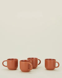 Four Hawkins New York Essential Mugs in Terracotta (set of 4) are arranged in a row on a light surface with a plain off-white background.