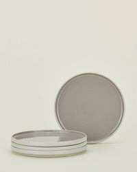 Three stacked Hawkins New York Essential Salad Plates in Light Grey and one upright plate from the set of four are shown against a plain light background. The plates feature a gray color with a white rim.