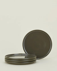 A set of four olive Essential Salad Plates from Hawkins New York, with one plate propped upright against a plain light background.