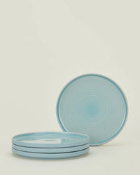 A set of four Hawkins New York Essential Salad Plates in Sky, made of stoneware with concentric patterns, are stacked neatly with one plate displayed upright against a plain background.