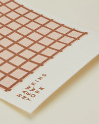 A set of 6 eco-friendly rectangular Essential Swedish Dishcloths in blush and terracotta with a brown grid pattern and “Hawkins New York” printed in the corner.