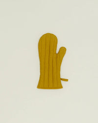 A Simple Linen Oven Mitt in Mustard by Hawkins New York, featuring vertical stitching and heat-resistant padding, lies flat on a plain light background.