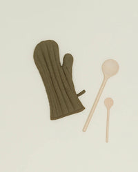 An olive Simple Linen Oven Mitt by Hawkins New York with heat-resistant padding is placed next to a large and a small wooden spoon on a plain light background.