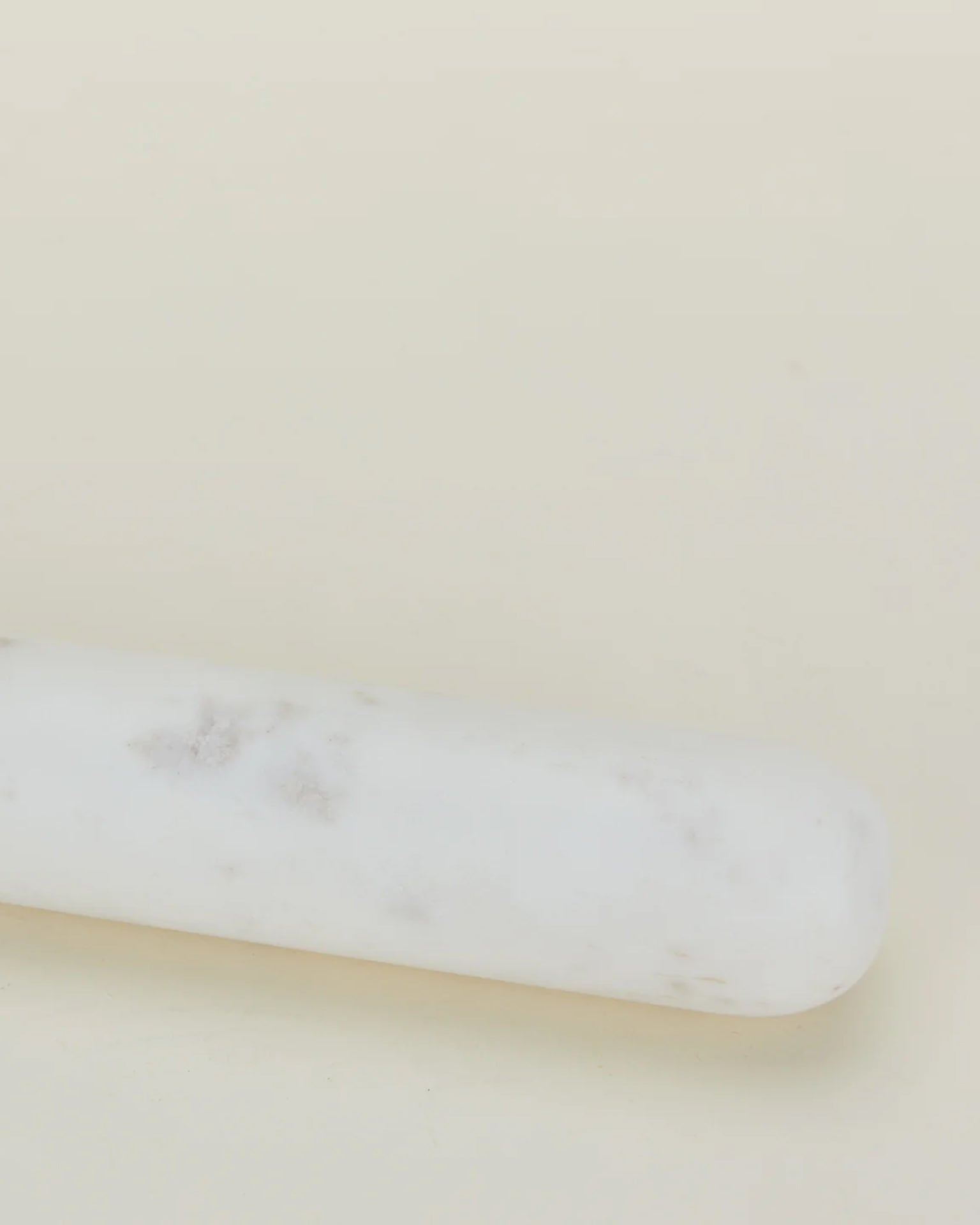 A close-up of the Hawkins New York Simple Marble Rolling Pin, featuring subtle gray veining and set diagonally against a light beige background.