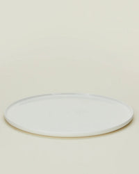 A set of four Simple Porcelain Dinner Plates by Hawkins New York is shown on a light beige background, each plate round, plain, white, and photographed from a slightly elevated angle.