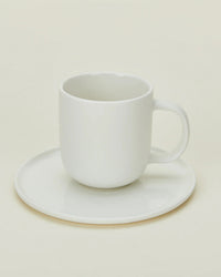 The Hawkins New York Simple Porcelain Espresso Cups & Saucers - Set of 2 features elegant white cups on matching saucers, pictured against a soft, neutral background.