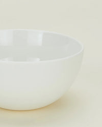 A portion of a Simple Porcelain Large Bowl from Hawkins New York’s set of 4 is shown on a light, neutral background, highlighting its smooth, glossy finish and minimalist style.