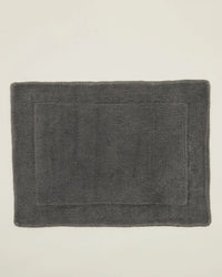 A Simple Terry Bath Mat in Dark Grey by Hawkins New York, made from soft cotton with a subtle border, is displayed on a plain light-colored surface.