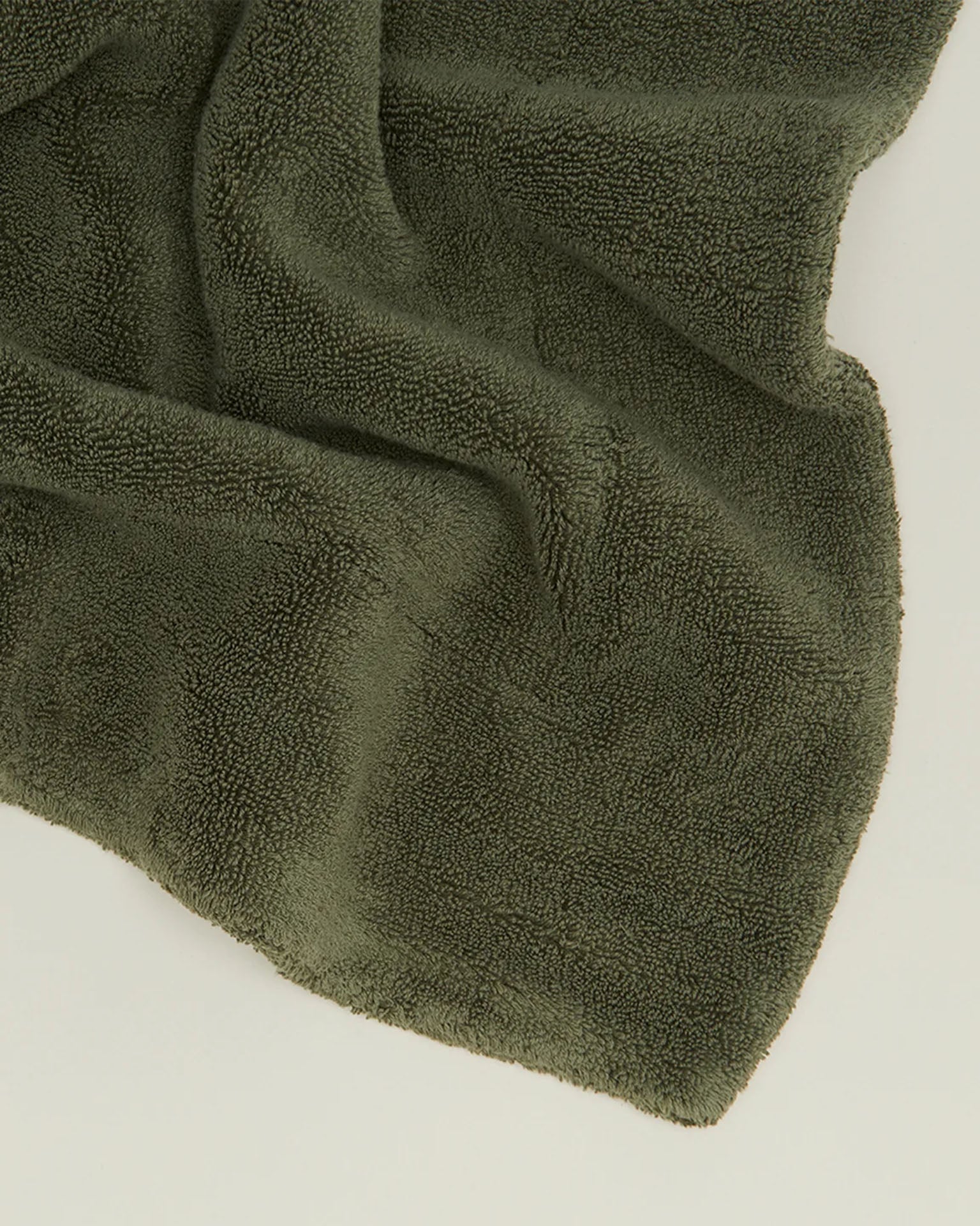 The Hawkins New York Simple Terry Bath Mat in Olive is spread out on a light surface.