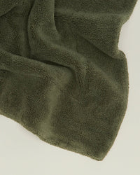 The Hawkins New York Simple Terry Bath Mat in Olive is spread out on a light surface.