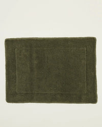 A rectangular Simple Terry Bath Mat in Olive from Hawkins New York, crafted from soft cotton with a simple border design, is shown on a plain light background.