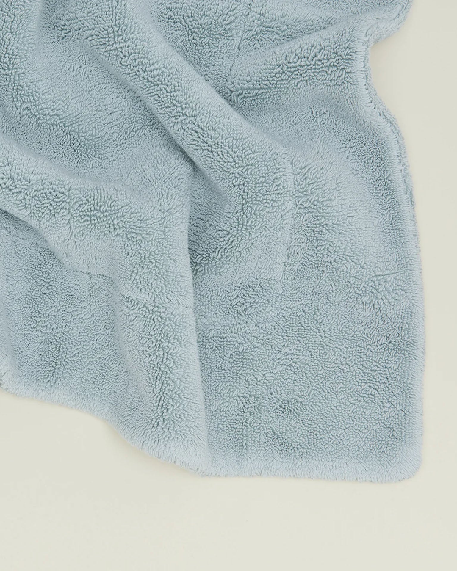 A light blue Simple Terry Bath Mat in Sky from Hawkins New York is spread out on a light-colored surface.