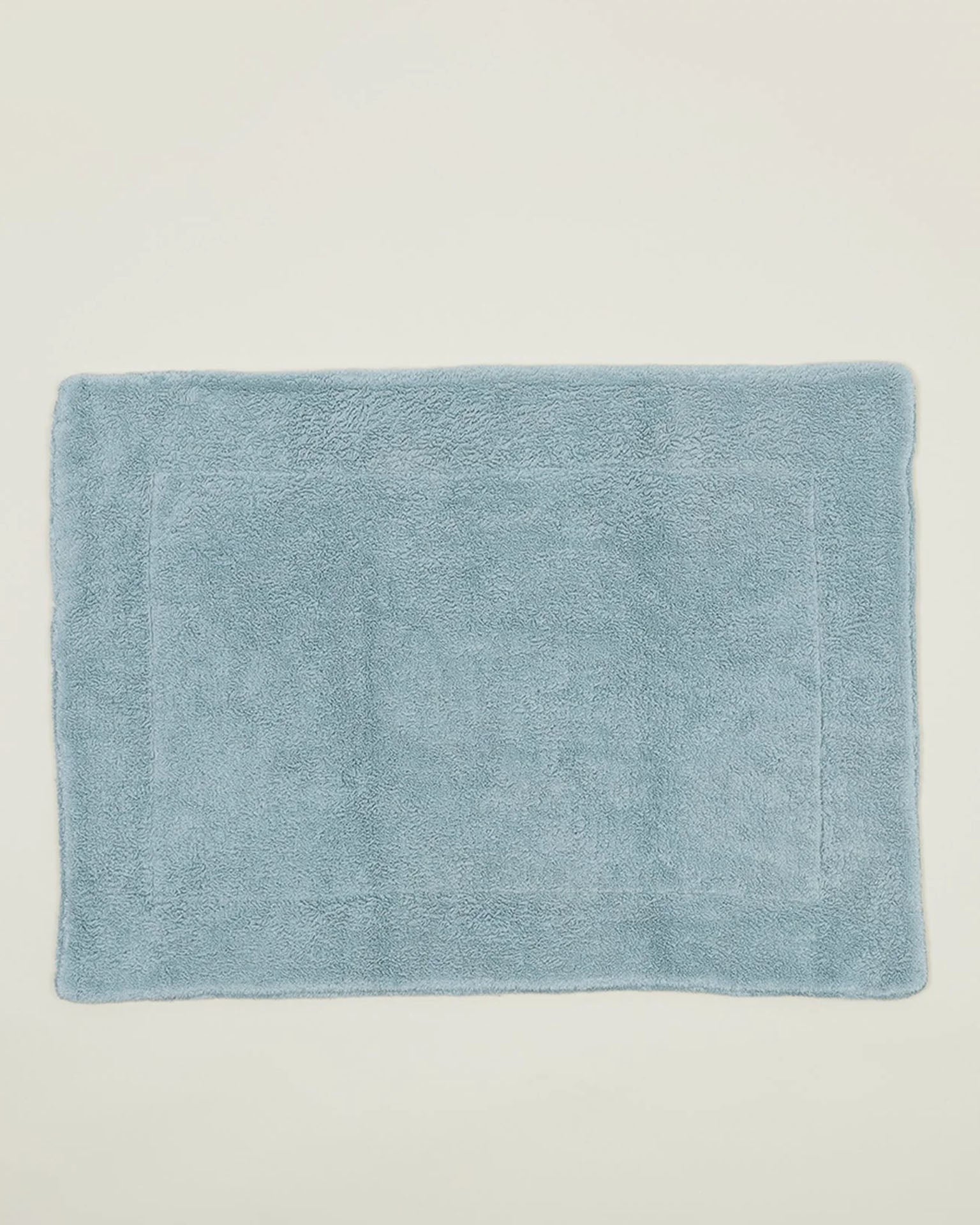 The Hawkins New York Simple Terry Bath Mat in Sky, featuring a soft, plush texture and rectangular shape, is displayed against a plain off-white background.