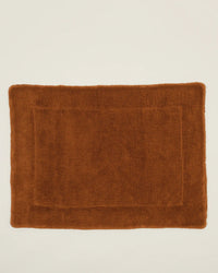 A rectangular Simple Terry Bath Mat in terracotta cotton with a textured border, shown on a white background. From Hawkins New York.