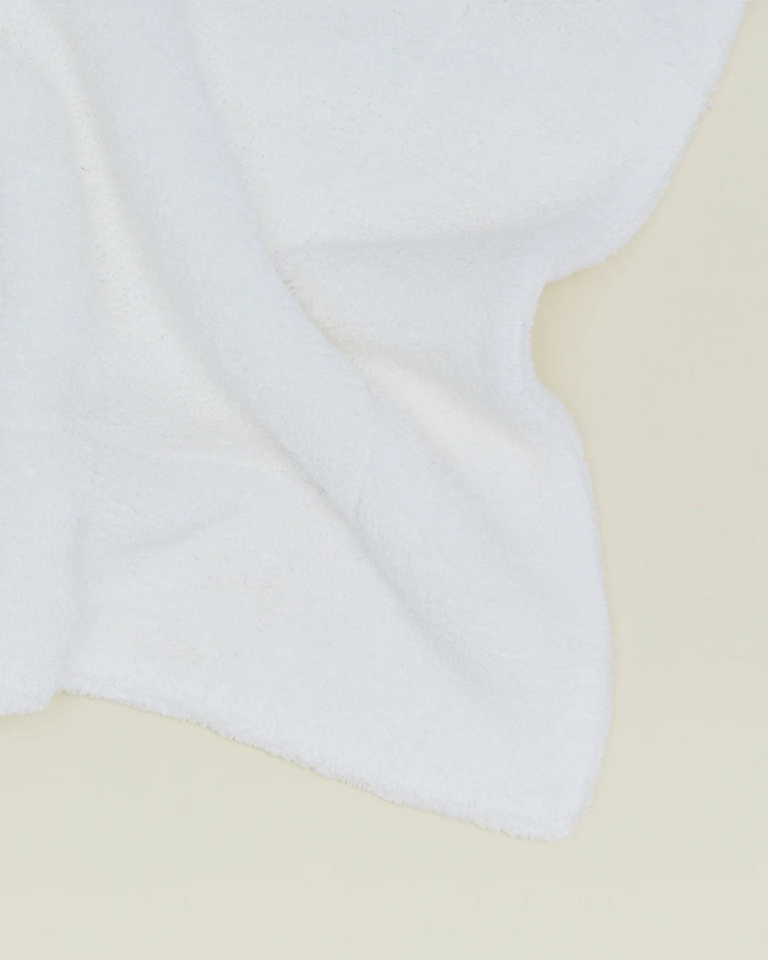 A Simple Terry Bath Mat in White from Hawkins New York, featuring a soft, textured surface, is displayed on a light beige background.