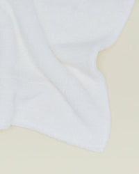 A Simple Terry Bath Mat in White from Hawkins New York, featuring a soft, textured surface, is displayed on a light beige background.