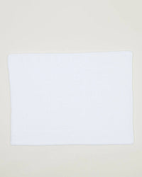 The Hawkins New York Simple Terry Bath Mat in White, crafted from cotton, is laid flat on a light-colored surface.