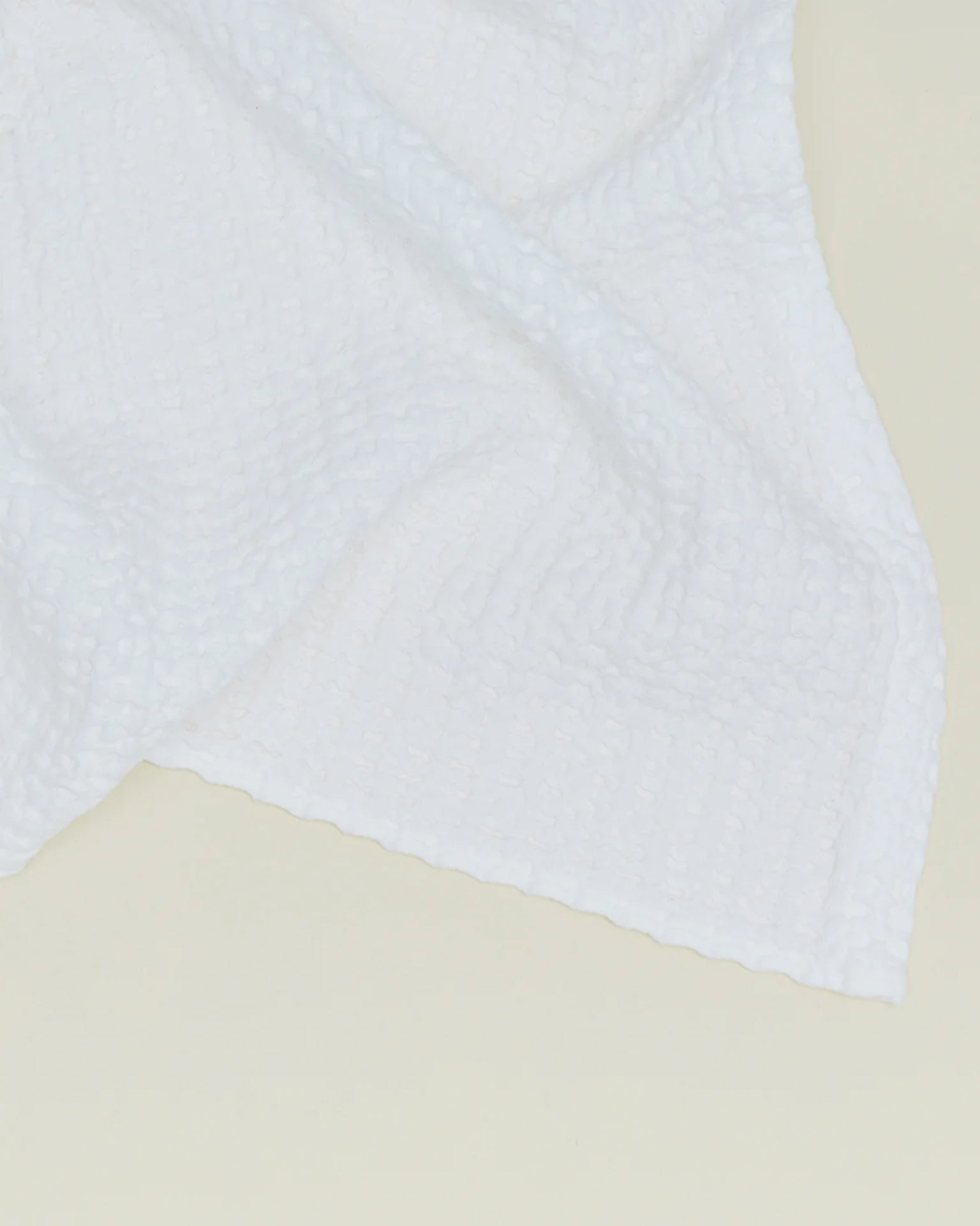 The Simple Waffle Bath Towel in White by Hawkins New York, made in Portugal, features a subtle grid texture and is shown draped against a light, neutral background.
