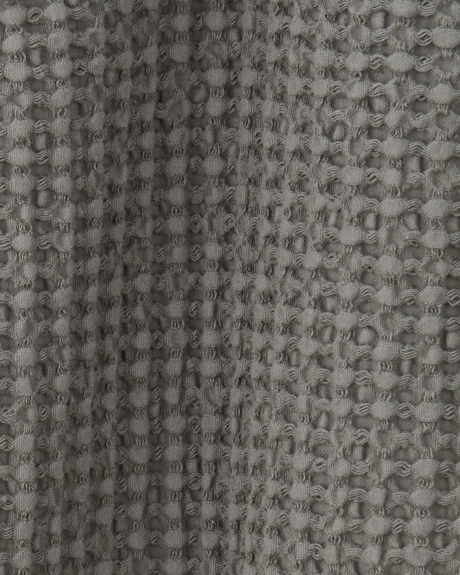 Close-up of the textured fabric with a waffle weave pattern on the Hawkins New York Simple Waffle Shower Curtain in Dark Grey.