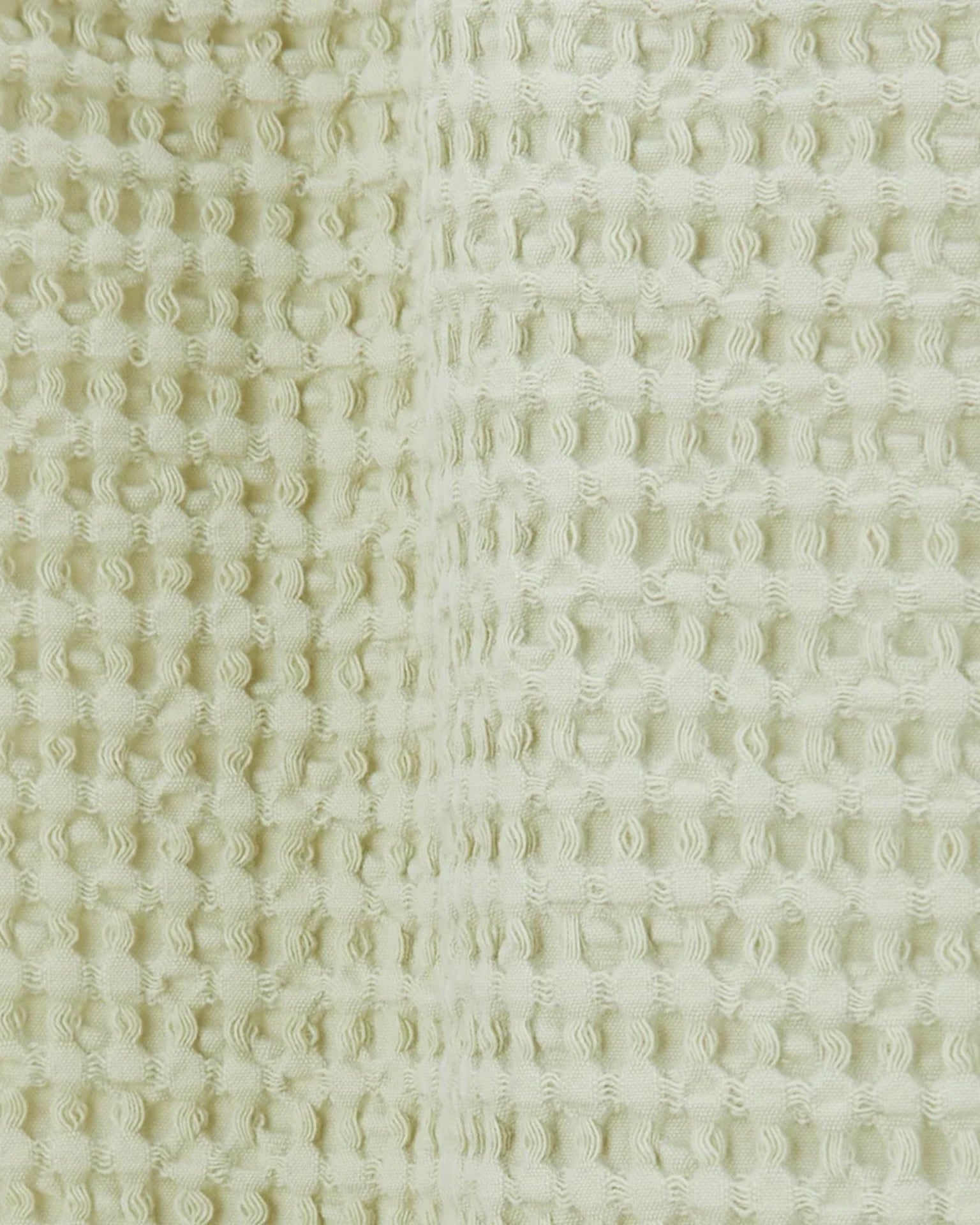Close-up of the Simple Waffle Shower Curtain in Sage by Hawkins New York, featuring a textured cotton fabric with a distinctive waffle pattern.