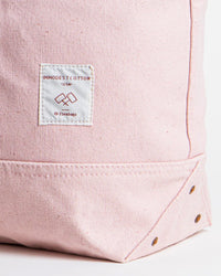 Close-up of the IMMODEST COTTON Large East West Tote in Bubblegum, featuring a white patch label reading IMMODEST COTTON USA and metal rivets on the bottom corner.