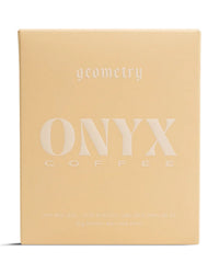 A beige 10oz bag of Onyx Coffee Lab Geometry features minimalist white text, labeled as light roast whole bean coffee for espresso or filter brewing.