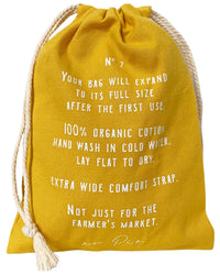 The French Market Bag No.2 In Yolk by PILLOWPIA features organic cotton, white text print, expands after first use, wide strap, multipurpose use, and should be washed in cold water—a modern update to the classic net bag.
