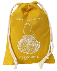 The French Market Bag No.2 in Yolk by PILLOWPIA is a yellow drawstring bag with white rope, featuring a vintage net bag design on the front. Made from organic cotton for sustainable style.
