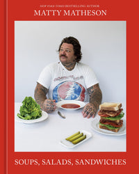 A tattooed man sits at a table enjoying tomato soup, salads, pickles, and a stacked sandwich. On the table is Soups, Salads, Sandwiches by Random House.