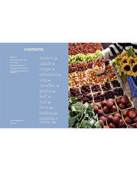 At a bustling market stall with fresh produce like tomatoes, plums, and greens, someone holds yellow fruits—great inspiration for recipes from The Wishbone Kitchen Cookbook by Random House.