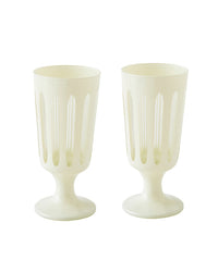 The SIR / MADAM Empire Footed Ale Powder Set/2 features two white goblets with vertical oval cutouts, thick stems, and round bases—ideal for serving craft cocktails in style.