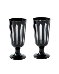 The Empire Footed Ale Tuxedo Set/2 by SIR / MADAM features two black glass goblets with vertical cutout patterns and a short pedestal base, reminiscent of classic Empire designs, shown side by side on a white background.