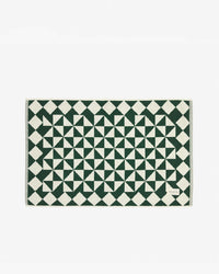 The Slowtide Gatsby Bath Mat in Sequoia is a rectangular, ultra-soft bath mat featuring a green and white geometric pattern, crafted from sustainably sourced cotton and shown on a plain white background.