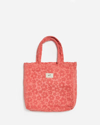 The Ginny Terry Tote Bag in Guava by Slowtide features a textured floral pattern, two handles, and a front label. Made from sustainably sourced cotton, its shown against a plain white background.